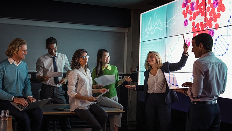 A group of 6 people at work looking at a display screen.