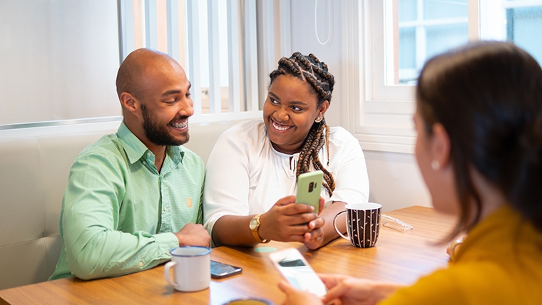 Two people smile while sharing content on a cellphone